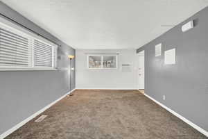 Carpeted spare room with a wall unit AC and a textured ceiling