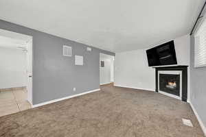 Unfurnished living room with light carpet and a textured ceiling