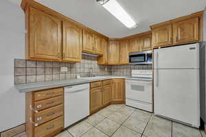 Kitchen with tasteful backsplash, white appliances, a textured ceiling, sink, and light tile patterned floors