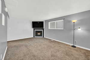 Unfurnished living room featuring carpet floors and a textured ceiling