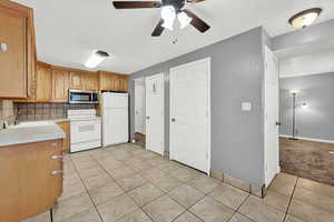 Kitchen featuring ceiling fan, sink, backsplash, white appliances, and light tile patterned flooring