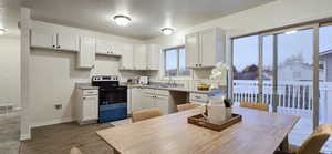 Kitchen featuring white cabinetry, sink, dark hardwood / wood-style floors, range with electric stovetop, and a textured ceiling