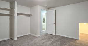 Unfurnished bedroom featuring carpet flooring, a textured ceiling, and a closet