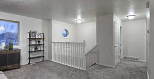 Hall with carpet and a textured ceiling