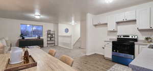 Kitchen with stainless steel range with electric stovetop, light hardwood / wood-style floors, and white cabinets