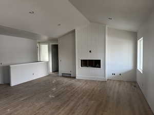 Unfurnished living room with hardwood / wood-style flooring and vaulted ceiling