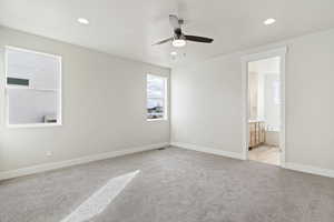 Interior space featuring light carpet, ensuite bath, and ceiling fan