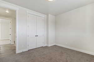 Unfurnished bedroom featuring light carpet and a closet