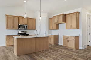 Kitchen with light wood-type flooring, stainless steel appliances, sink, a center island with sink, and lofted ceiling