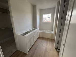 Bathroom with a tub to relax in, hardwood / wood-style flooring, a textured ceiling, and vanity