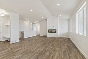 Unfurnished living room with a fireplace, light hardwood / wood-style floors, and lofted ceiling