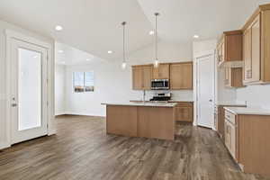 Kitchen with a kitchen island with sink, vaulted ceiling, hardwood / wood-style flooring, appliances with stainless steel finishes, and decorative light fixtures