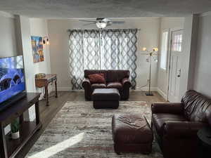 Living room with ceiling fan, hardwood / wood-style floors, and a textured ceiling