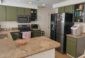 Kitchen featuring kitchen peninsula, stainless steel appliances, light tile patterned floors, and green cabinetry