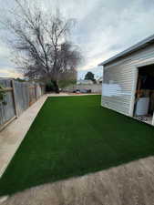 View of yard with central air condition unit and artificial turf