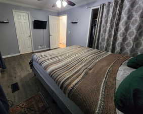 Master bedroom featuring dark hardwood / wood-style floors, ceiling fan, crown molding, and bathroom