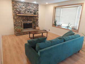 Living room with hardwood / wood-style floors and a stone fireplace