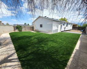 Rear view of property featuring artificial turf