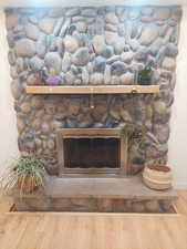 Room details with hardwood / wood-style floors and a stone fireplace