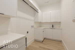 Laundry room featuring sink, cabinets, electric dryer hookup, hookup for a washing machine, and light hardwood / wood-style floors