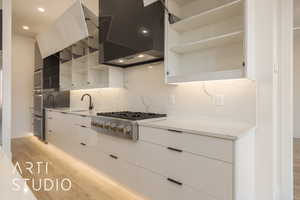 Kitchen featuring white cabinetry, light hardwood / wood-style flooring, ventilation hood, decorative backsplash, and appliances with stainless steel finishes