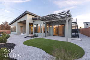 Back house at dusk featuring a pergola, a lawn, and a patio