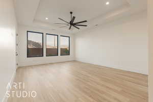 Unfurnished room featuring light hardwood / wood-style floors, a raised ceiling, and ceiling fan