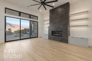 Unfurnished living room with a mountain view, light hardwood / wood-style flooring, ceiling fan, and a tiled fireplace