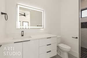 Bathroom featuring tile patterned floors, a tile shower, vanity, ceiling fan, and toilet