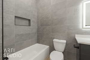 Bathroom with vanity, toilet, and tile walls