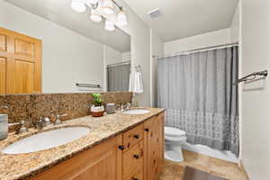 Bathroom featuring tile patterned flooring, vanity, toilet, and walk in shower