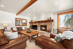 Living room with beam ceiling, light colored carpet, and a fireplace