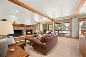 Living room featuring light carpet, a fireplace, beamed ceiling, and a textured ceiling