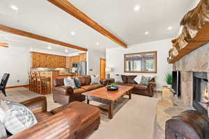 Living room featuring beam ceiling, a fireplace, and light carpet