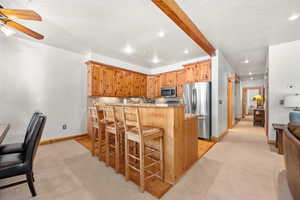 Kitchen with a kitchen bar, stainless steel appliances, tasteful backsplash, and light colored carpet