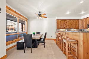 Dining area with ceiling fan and light colored carpet