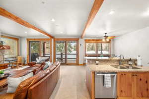 Kitchen featuring light carpet, stainless steel dishwasher, ceiling fan, sink, and beamed ceiling