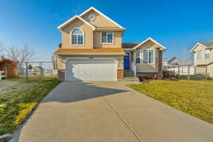 View of front of house featuring a front lawn and a garage