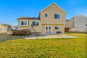 Rear view of house with a yard, a patio area, and french doors