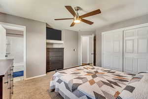 Bedroom with a textured ceiling, ceiling fan, light carpet, and ensuite bath