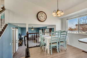 Dining space with a barn door, light hardwood / wood-style flooring, and ceiling fan with notable chandelier