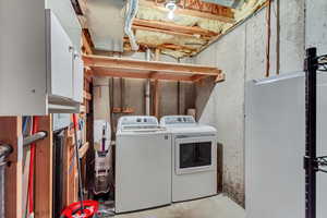 Clothes washing area featuring washer and clothes dryer and cabinets