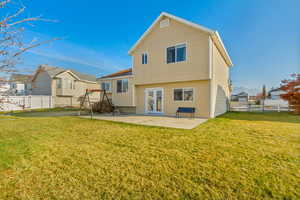 Rear view of property with a lawn and a patio