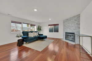 Living room with wood-type flooring and a stone fireplace