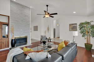 Living room with dark hardwood / wood-style flooring, ceiling fan, a fireplace, and high vaulted ceiling