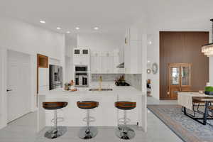 Kitchen featuring a breakfast bar, decorative light fixtures, stainless steel appliances, and sink