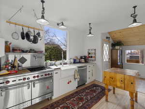 Kitchen featuring appliances with Wolf range, light wood flooring, and pendant lighting