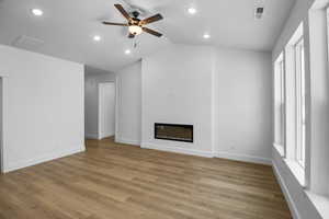 Unfurnished living room with ceiling fan, lofted ceiling, and light hardwood / wood-style flooring