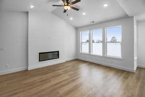 Unfurnished living room featuring light hardwood / wood-style floors, vaulted ceiling, and ceiling fan