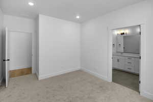 Unfurnished bedroom with light colored carpet and ensuite bath